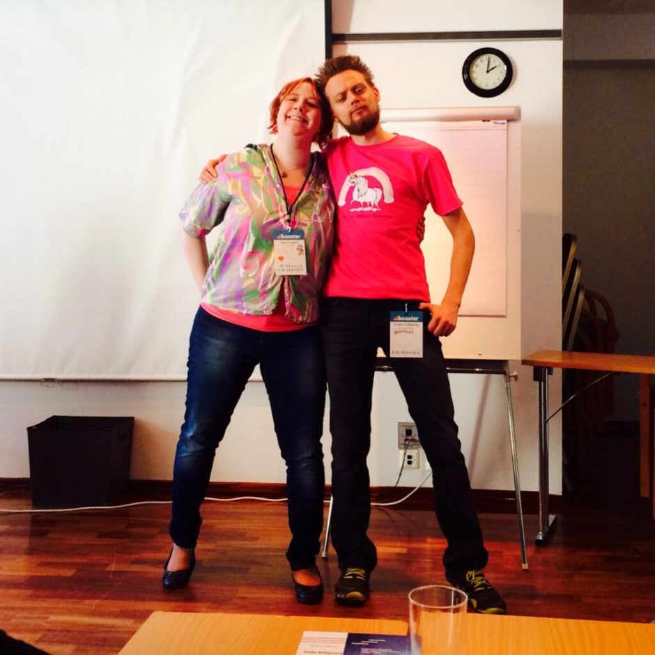 Picture of Gitte Klitgaard and Torbjörn Gyllebring before doing a workshop together. They are wearing tops with hot pink and dark jeans to match.They are standing with an arm around the other and smiling to the camera.
In the background is a flipchart and a screen.